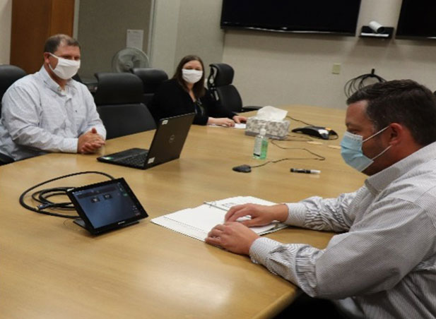 Staff in conference room with masks and social distancing