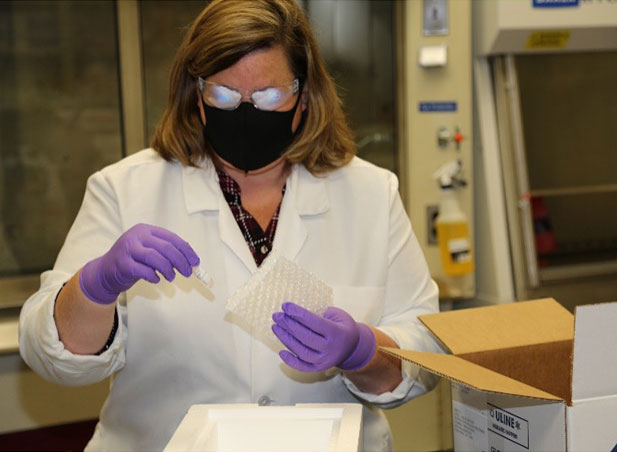 Quality assurance specialist wearing a lab coat prepares a vial