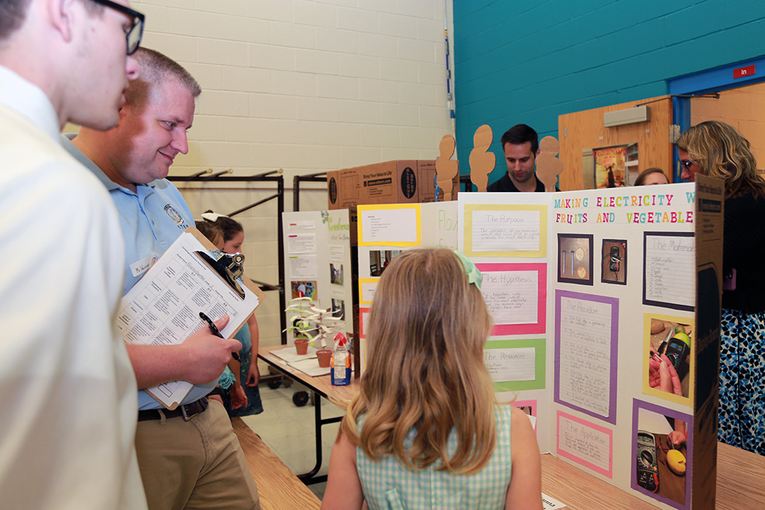 Mr. Casey Weininger, ECBC STEM/Outreach Coordinator judges a student's project during the science fair.