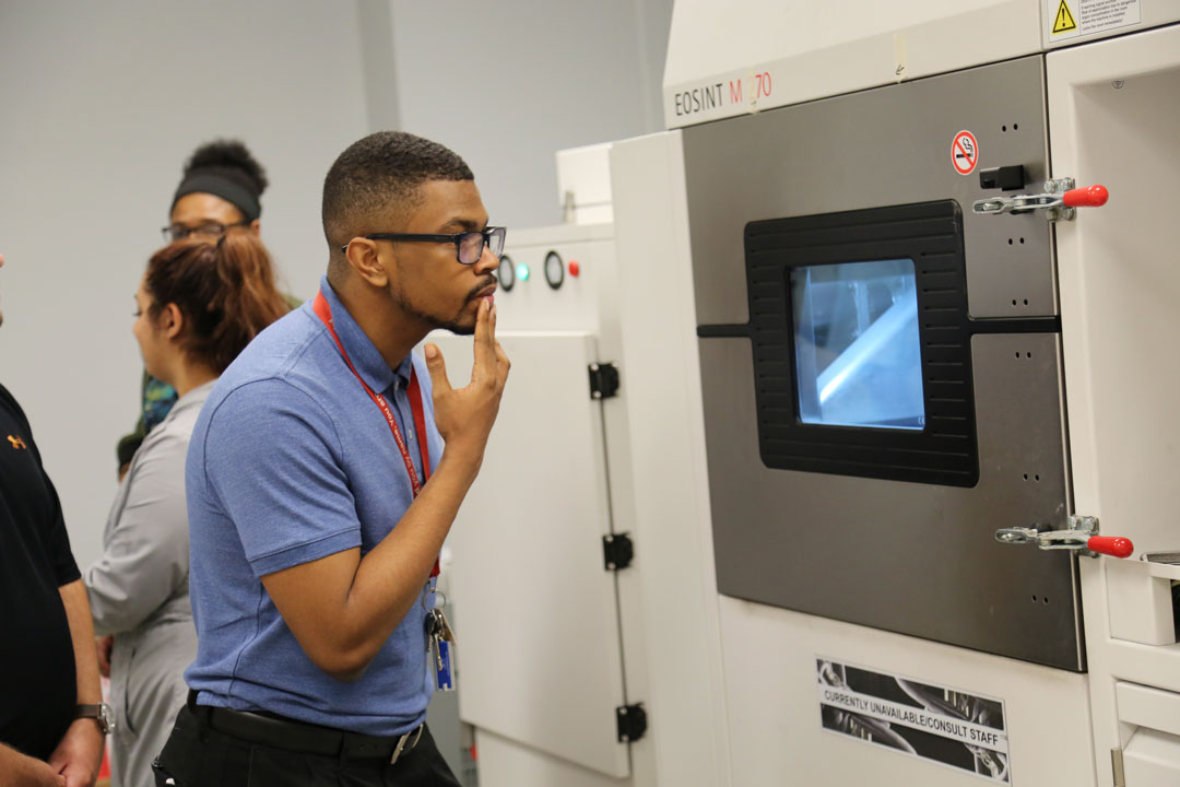 MUSIP intern Irving Baker takes a close look at one of the 3D printers in RDECOM C&B’s Additive Manufacturing Laboratory.