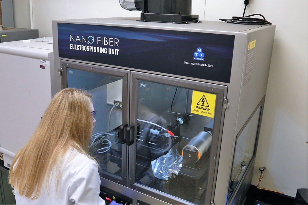Kuhn observes the electrospinning process as nanofibers are created. Photo credit: Brad Kroner