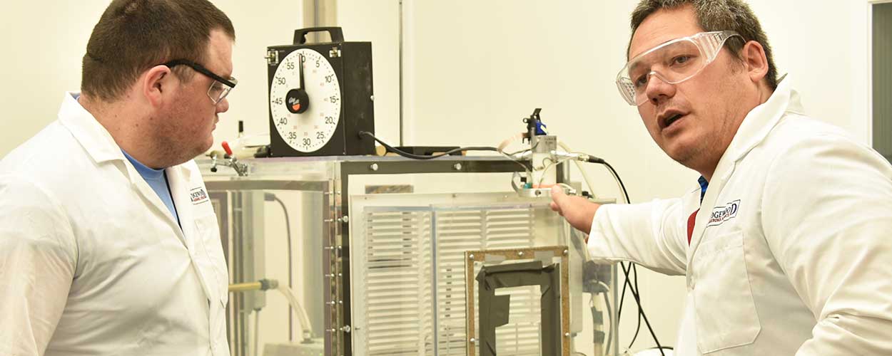 Jerry Cabalo, Ph.D. and high school teacher Tyler Dufrene work with an aerosol test chamber.