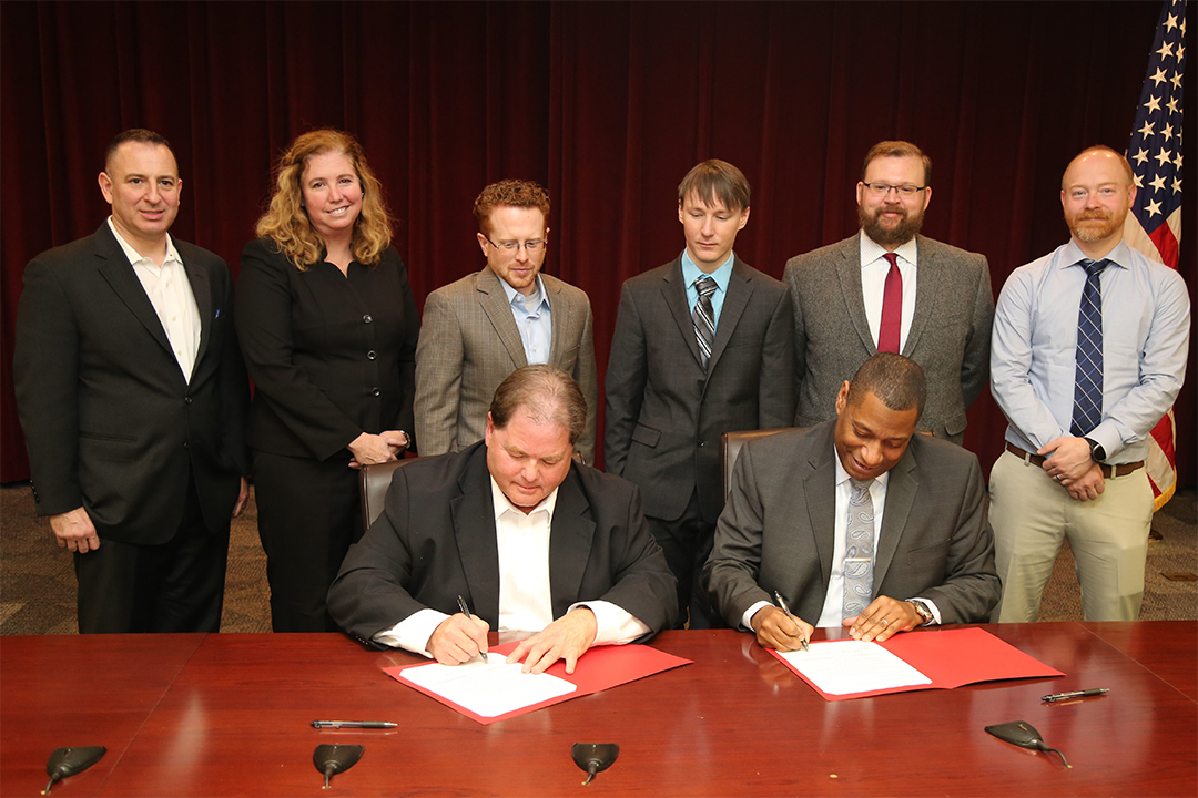 The inventors of RDECOM ECBC’s VOCkit observe the signing of agreements that will leverage that technology into a commercial biological reader. Pictured from left to right, back row: Peter Emanuel, Ph.D., Patricia Buckley, Ph.D., Gregory Thompson, Jacob Shaffer, Aleksandr Miklos, Ph.D., and Colin Graham. Sitting: Robert Baumgardner, PhD. and Eric L. Moore, Ph.D., Not pictured: Calvin Chue, Ph.D. (Photo Credit: RDECOM ECBC photo by Jack Bunja)