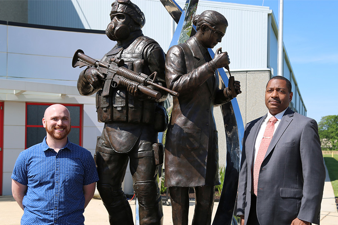 Statue designer Jason Gitlin stands with Eric L. Moore, Ph.D., Center director, in front of the statue honoring Soldier and scientist. (Photo credit: CCDC Chemical Biological Center photo by Jack Bunja.)