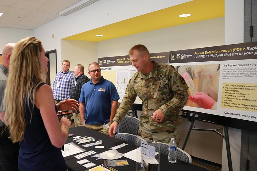 Sgt. 1st Class Robert Olson speaks with stakeholders about a new sample collection pouch developed at the Center.