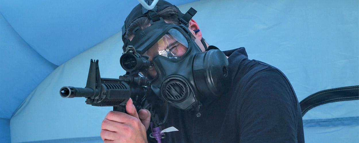 A civilian researcher fires rounds down range from within the inflatable chamber to test the chamber’s ability to properly contain aerosol simulant during a live-fire exercise.
