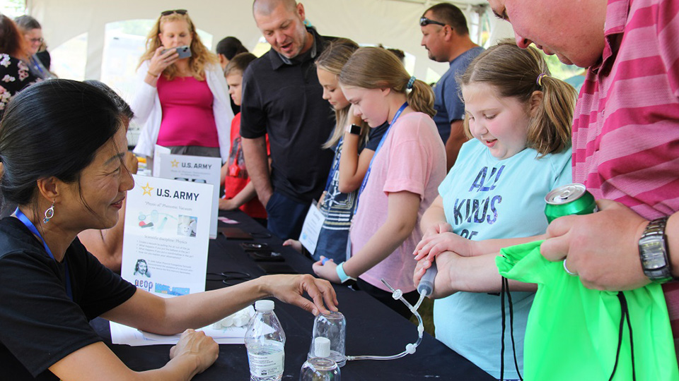 Stella Lee, a DEVCOM CBC program engineer, teaches children and families about air pressure by demonstrating its effects on a marshmallow at the Magic of Science Fair and Family Festival on June 10. (U.S. Army photo by Aeriel Storey)